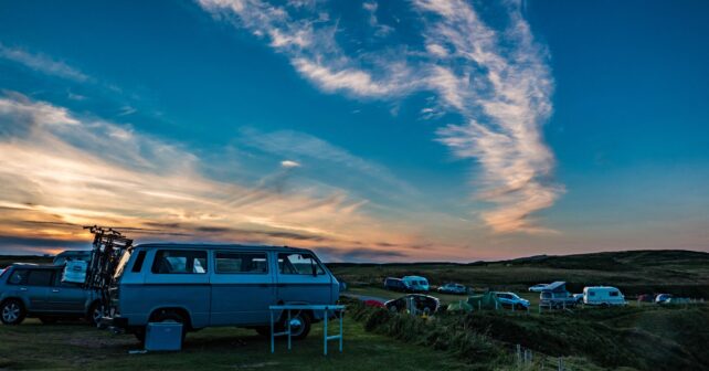 A scenic sunset view of Volkswagen campervans parked in Durness, Scotland.